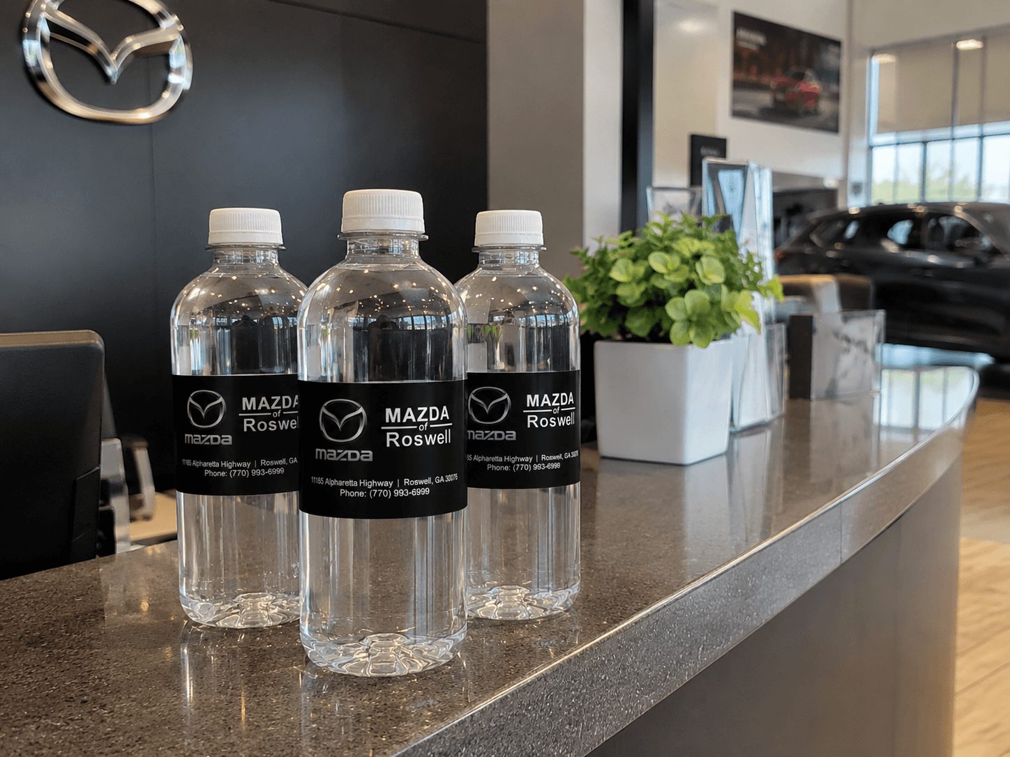 Custom-labeled water bottles on the reception counter at Mazda of Roswell