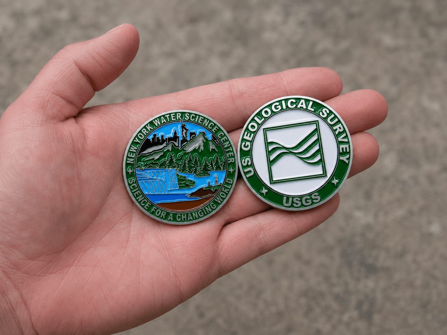 Enamel challenge coins held in a hand